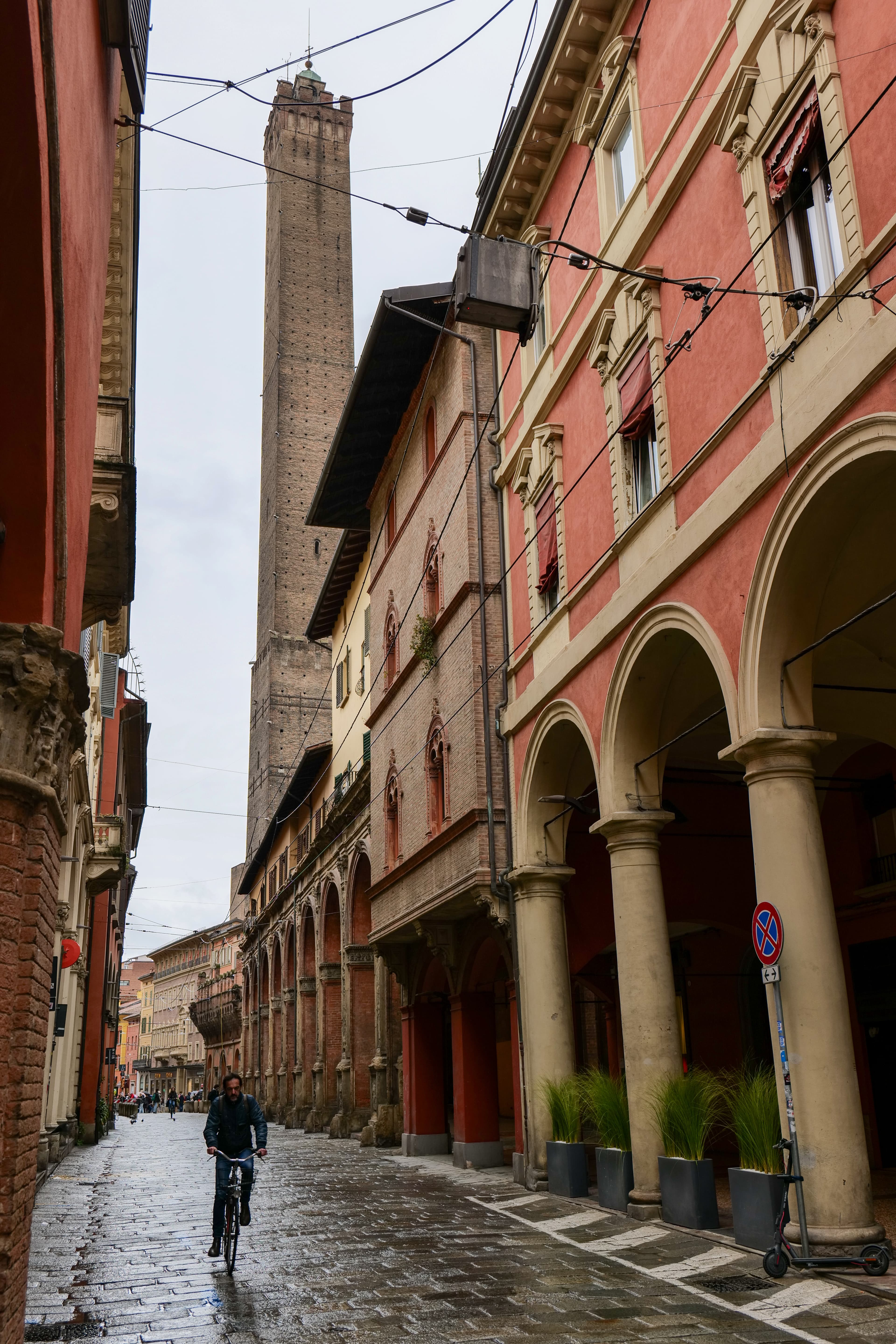 Bologna's medieval porticoes looking up a quiet street in the old centre, terracotta arches framing the view overhead