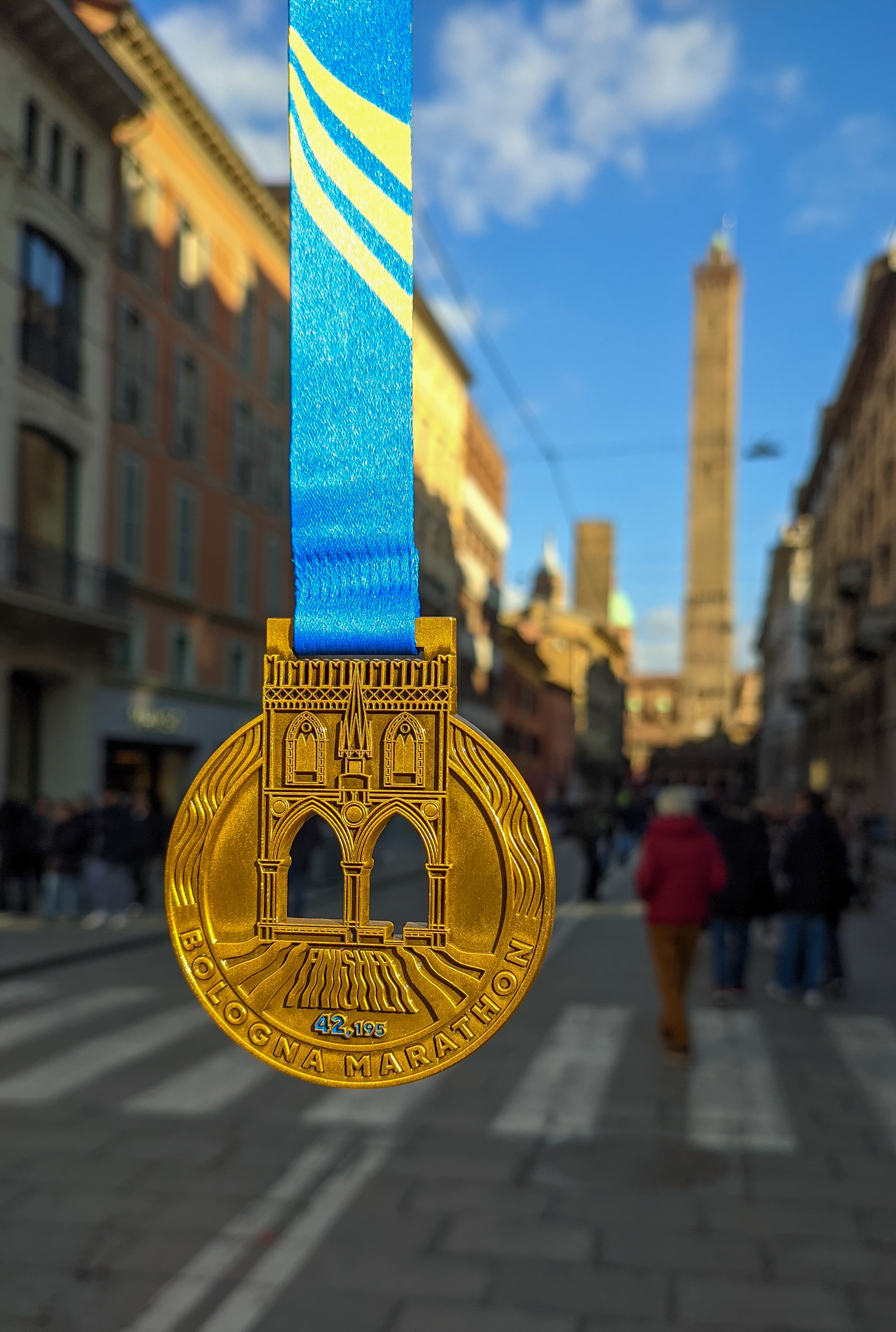 The Termal Bologna Marathon finisher medal, showing the Bologna towers and Piazza Maggiore design, held up against a blurred background