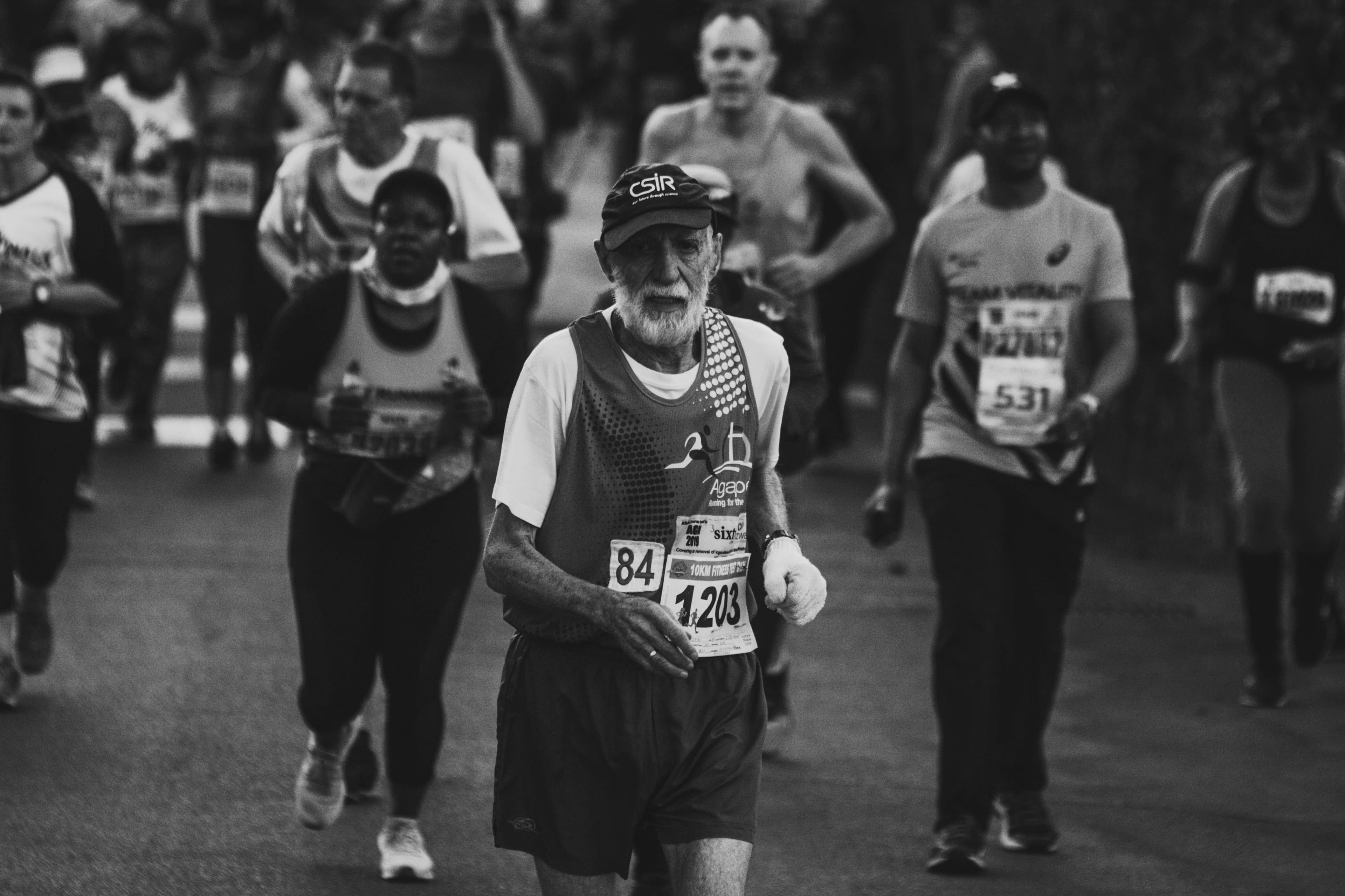 An older male runner competing in a road marathon, representing the self-selected, highly trained athletes who form the competitive age-group field at major races