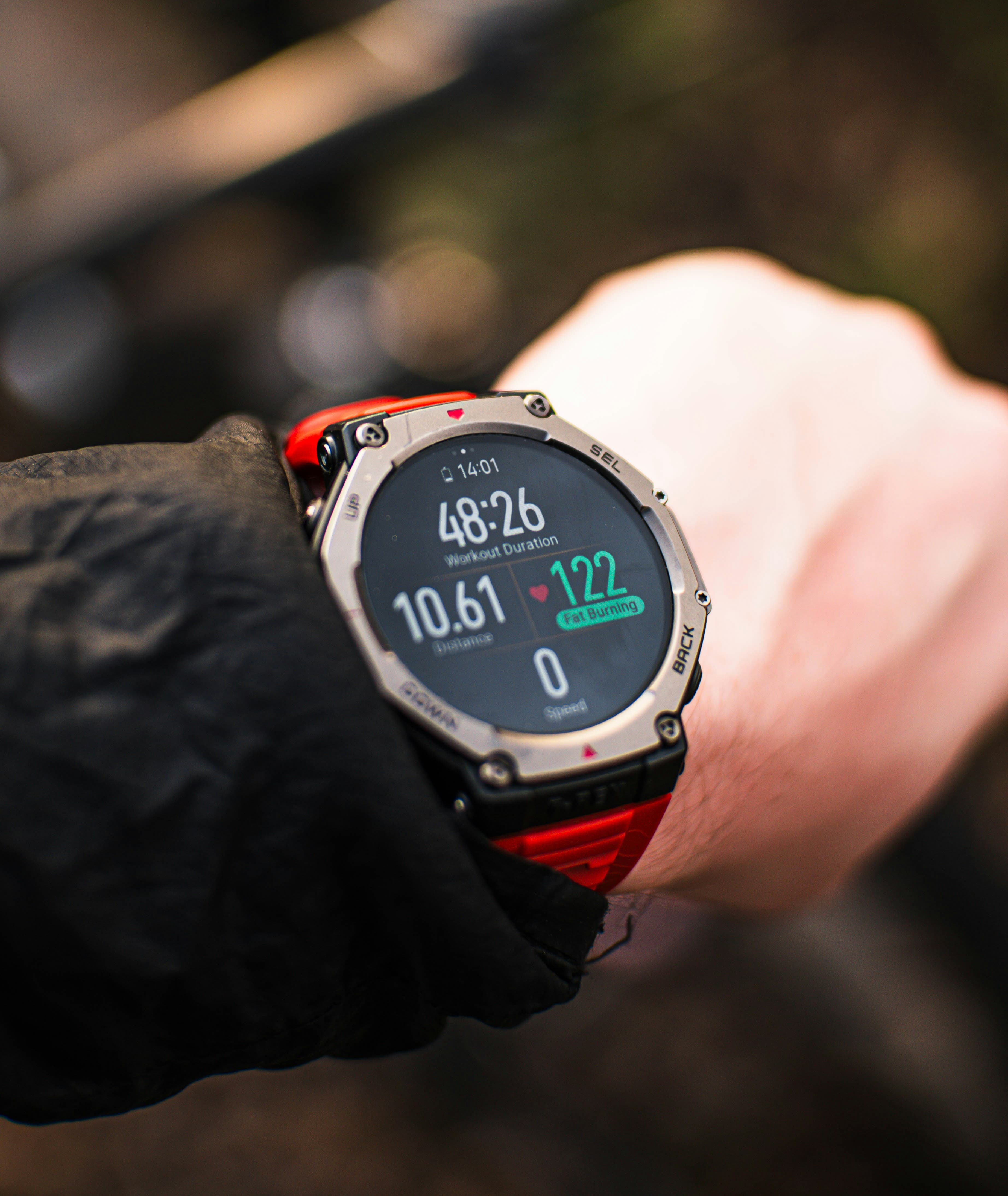 A runner glancing at a GPS running watch showing pace and distance data during a road run